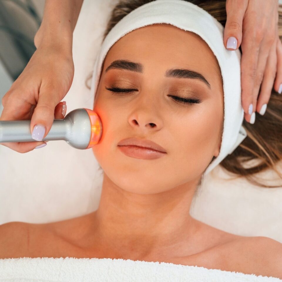 Trattamento viso con dispositivo a luce su una persona distesa con fascia nella testa.